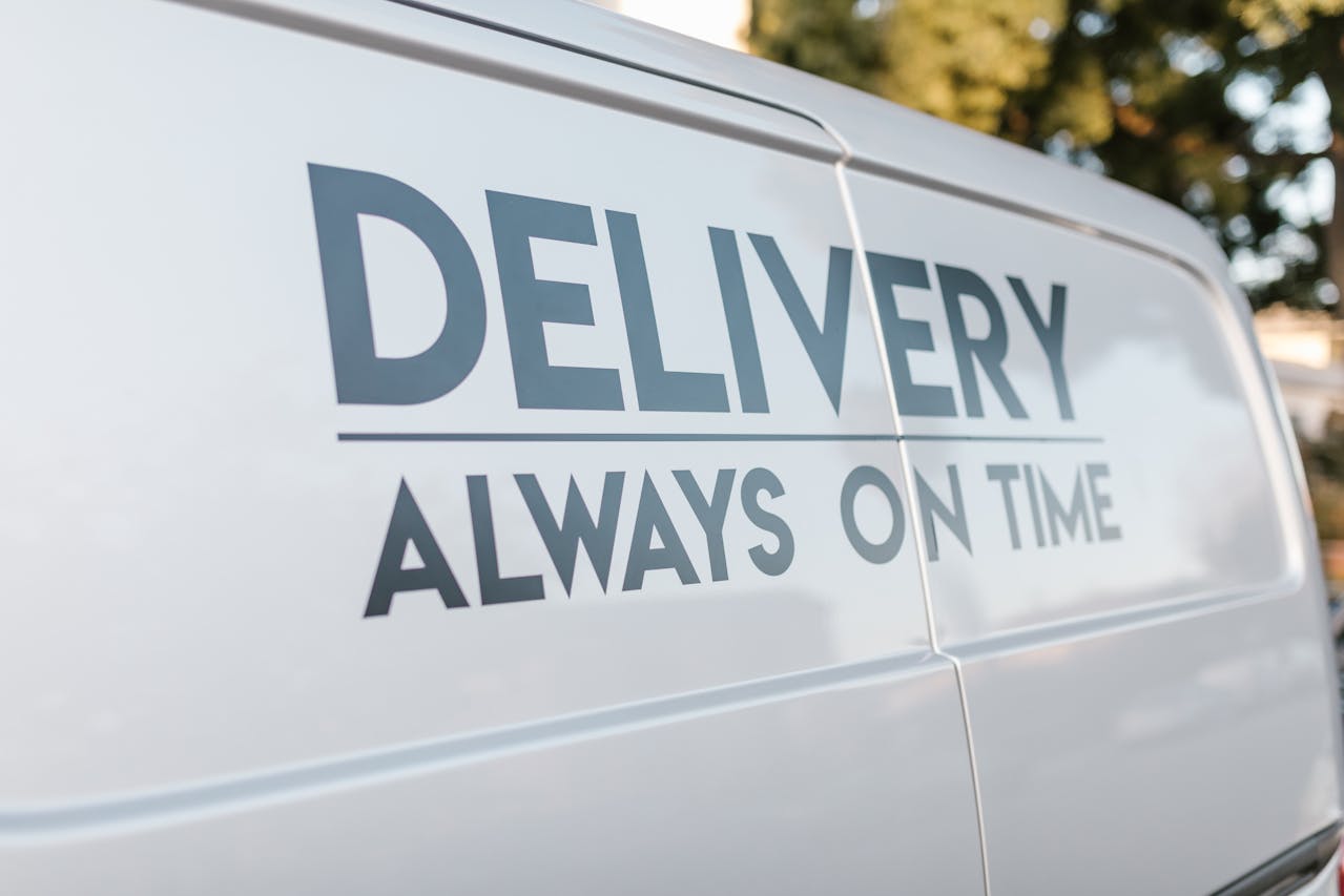 Bok białego samochodu dostawczego z napisem „DELIVERY ALWAYS ON TIME” – wizualizacja efektywnej logistyki i zarządzania dostawami z wykorzystaniem Dynamics 365 Business Central.